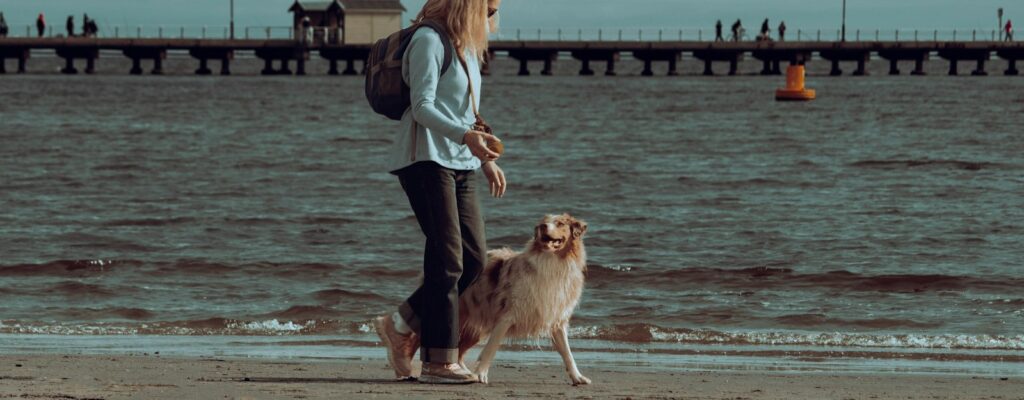a woman walking her dog on the beach